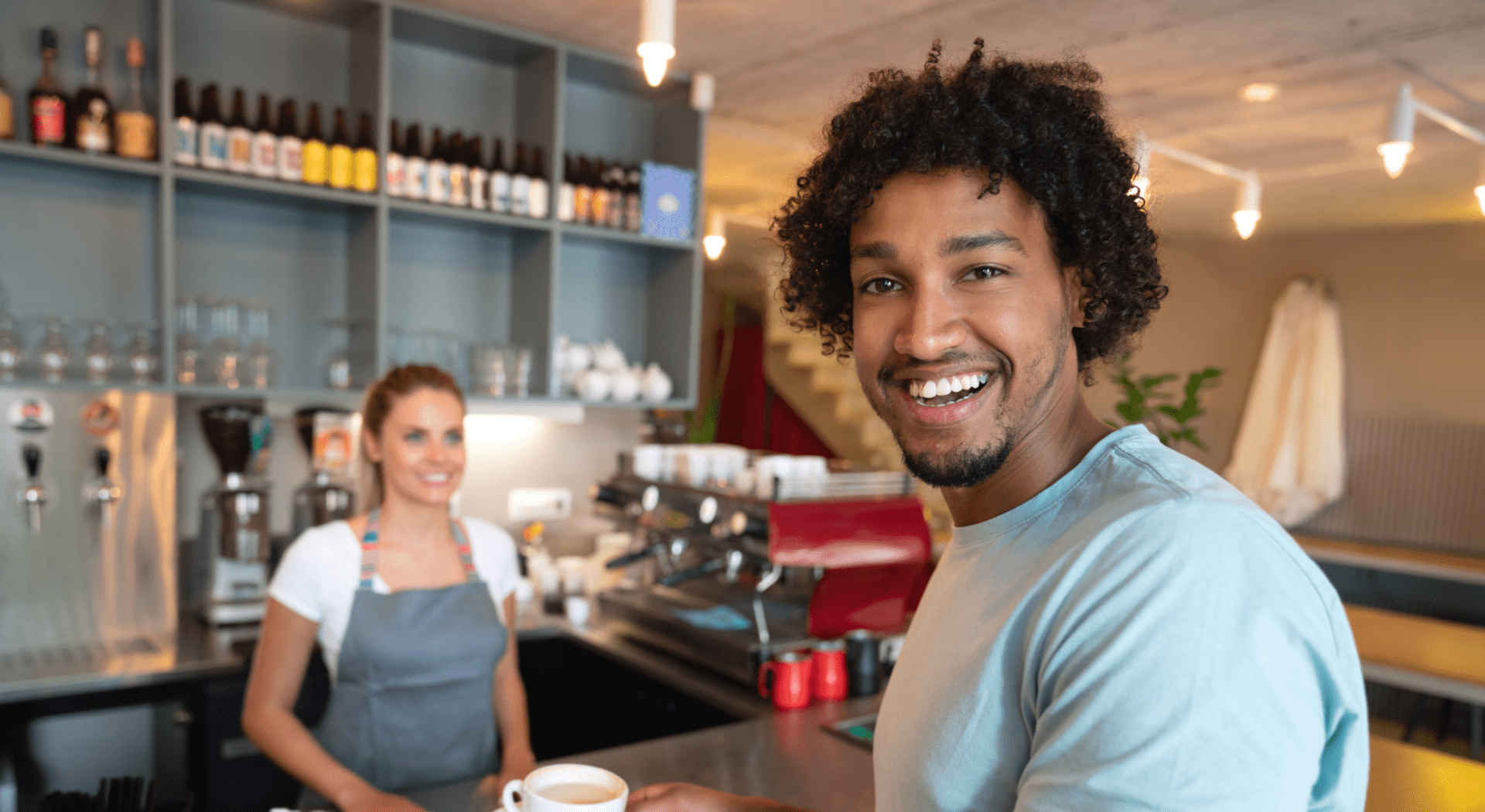 Man smiling with coffee at cafe counter.