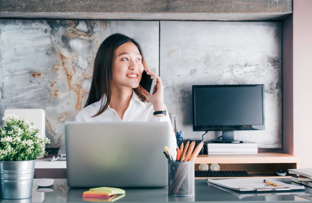 Woman talking on phone at office desk.